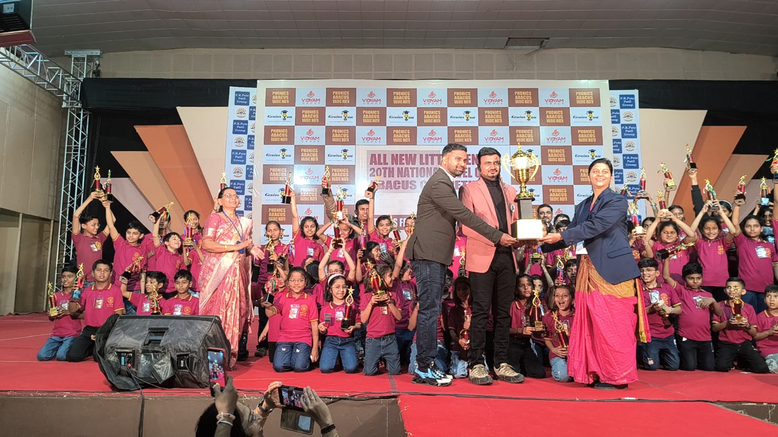 Pooja Bakale receiving award on stage with students at National Abacus Competition